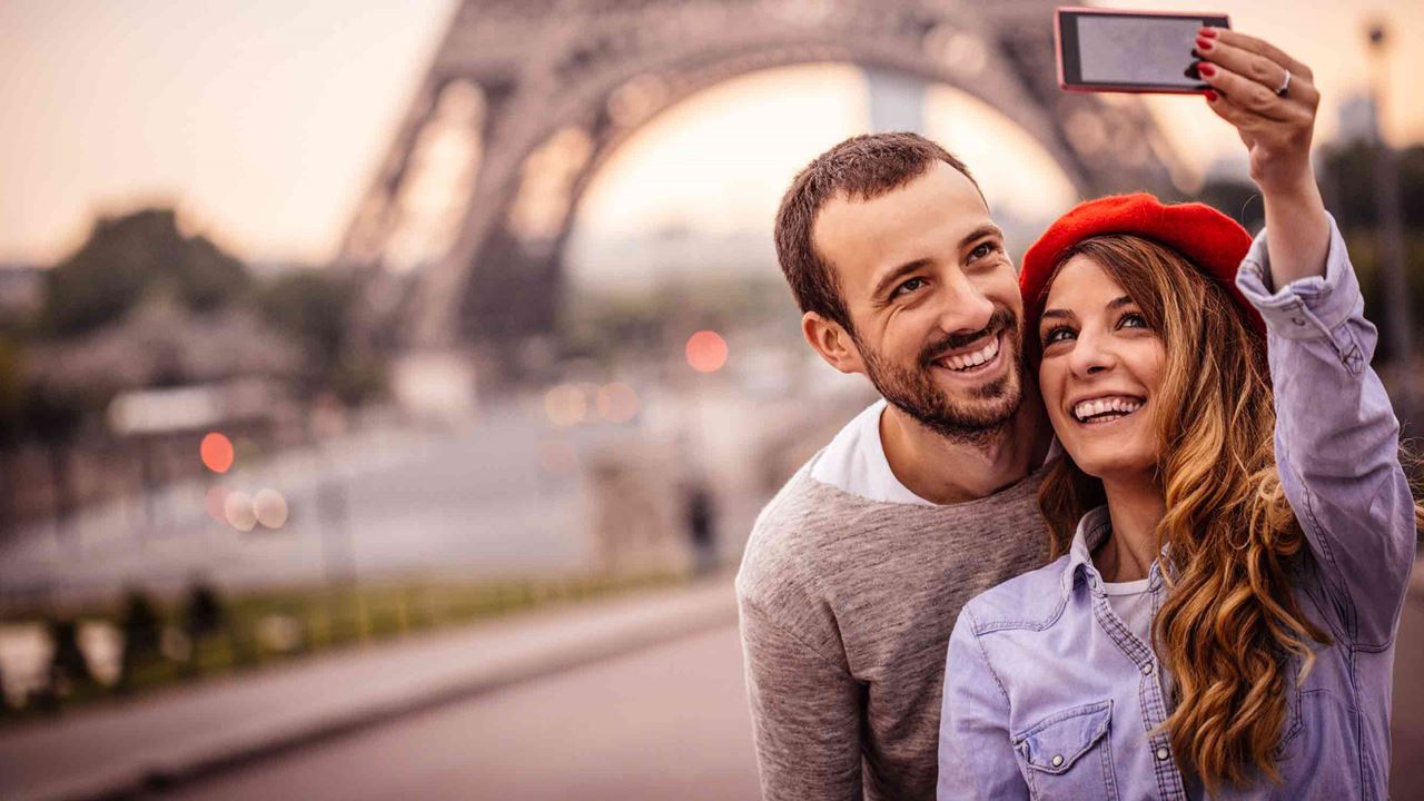 Smiling couple taking selfie in front of Eiffel Tower