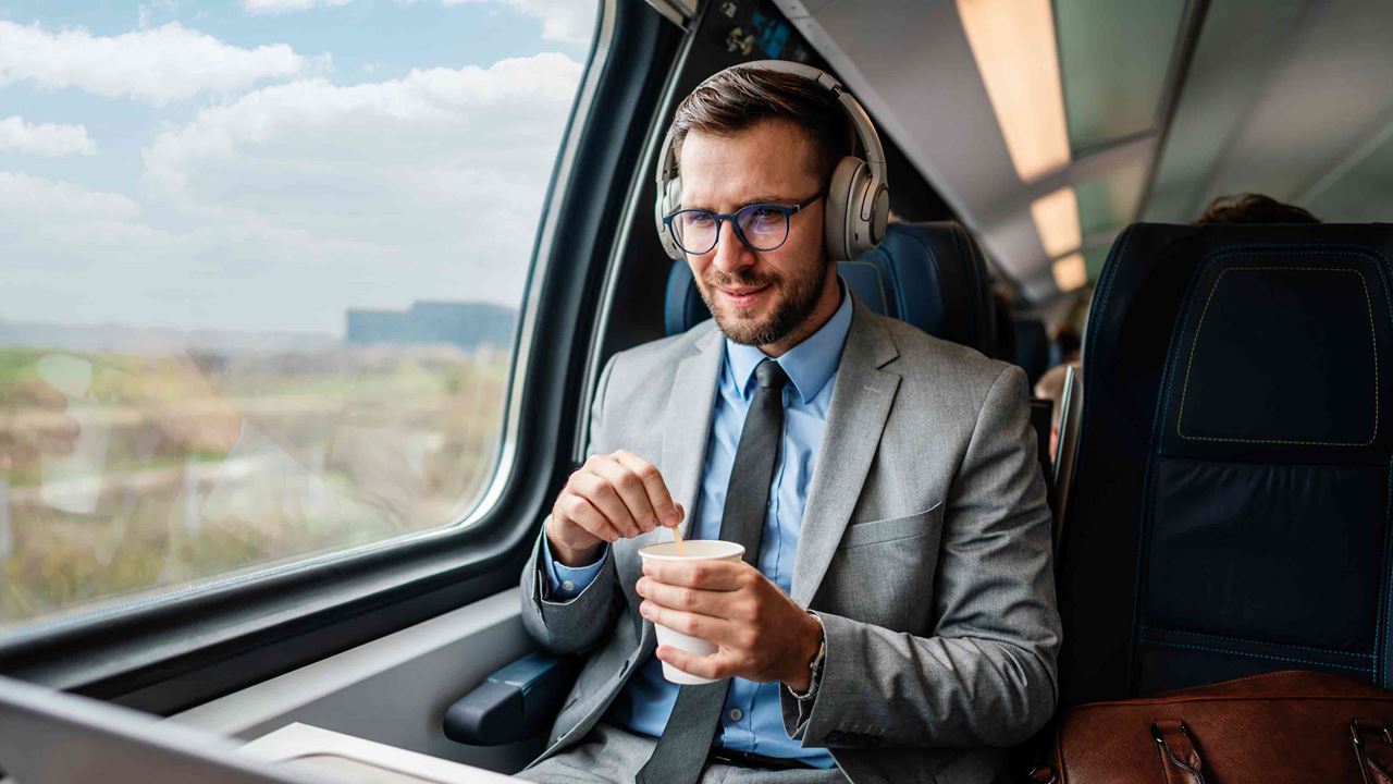 businessman-with-glasses-and-headphones-sitting-on-the-train-looking-at-laptop