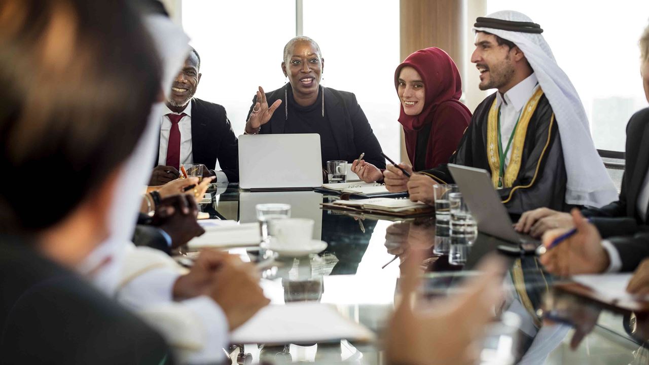 diverse-group-sitting-around-conference-table-smiling