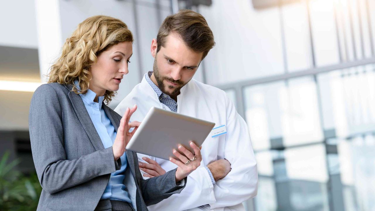 Doctor-and-employee-discussing-over-a-tablet