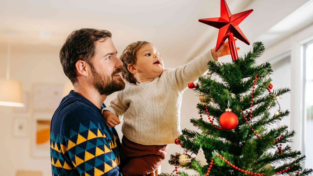 man-holding-child-placing-star-on-christmas-tree