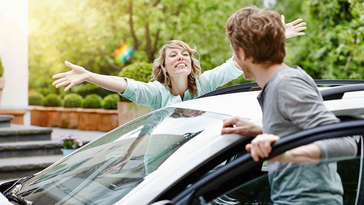 woman greeting man outside of car