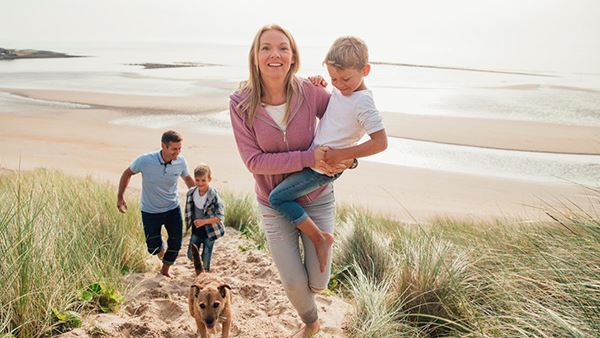 family walking dog on the beach