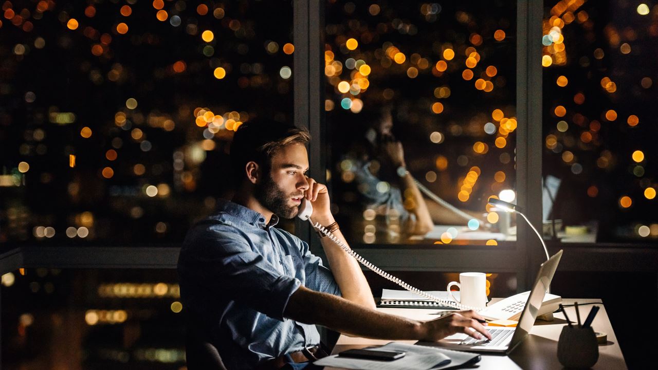 Man on phone in office with evening city view