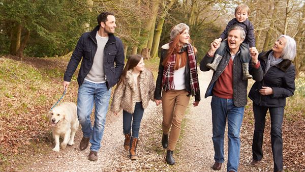 extended family walking their dog on an autumn wood path