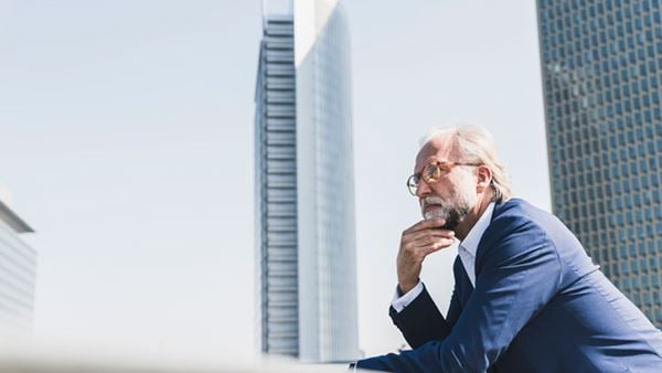 pensive mature businessman on a rooftop with skyscraper behind