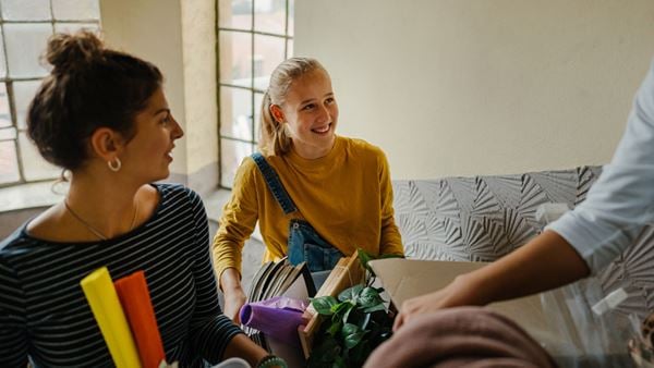 young woman smiling as she carries boxes into her new apartment